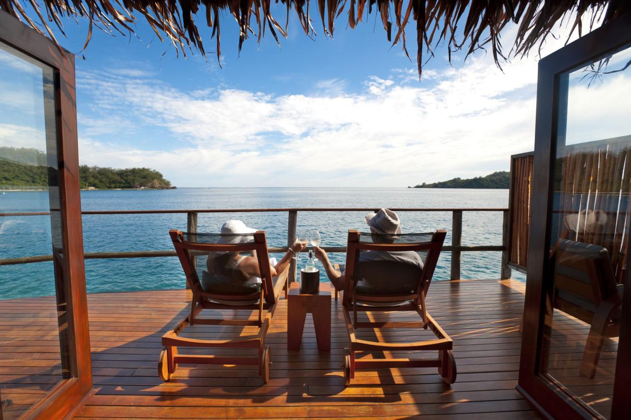 Couple relaxing on sun lounges in an over water bungalow