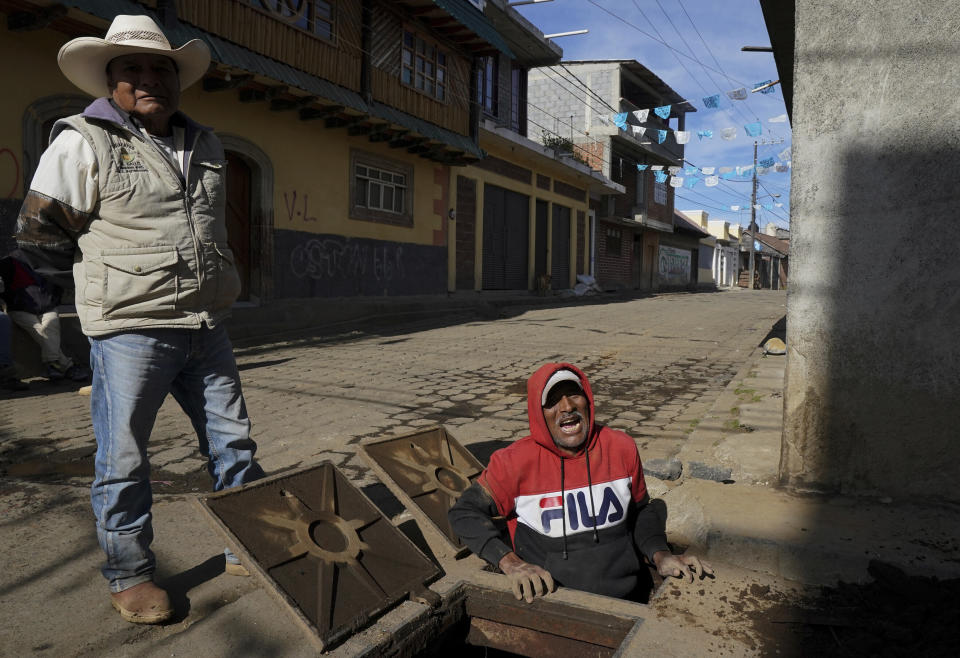 Municipal workers clean a sewer line in the Puerpecha Indigenous community of Comachuen, Mexico, Wednesday, Jan. 19, 2022. Money sent home by migrants working in the United States has allowed their families to remain in Comachuen rather than moving to other parts of Mexico for work. (AP Photo/Fernando Llano)