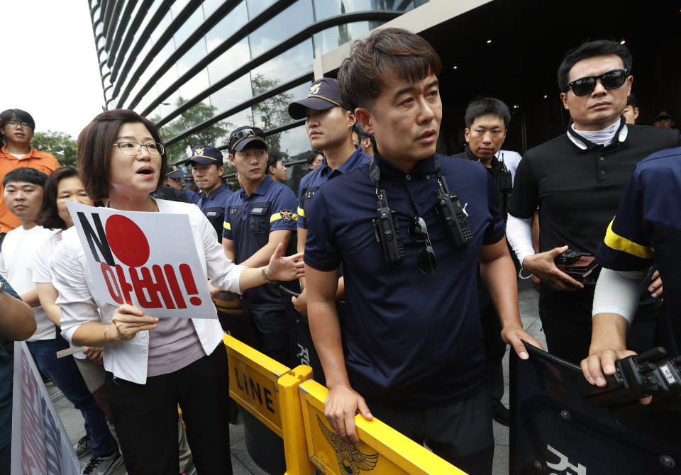 A South Korean protester argues with police officers during a rally against Japan in front of a building which houses Japanese embassy in Seoul, South Korea, Friday, Aug. 2, 2019. Japan's Cabinet on Friday approved the removal of South Korea from a "whitelist" of countries with preferential trade status, a move sure to fuel antagonism already at a boiling point over recent export controls and the issue of compensation for wartime Korean laborers. The sign reads " Japanese Prime Minister Shinzo Abe." (AP Photo/Ahn Young-joon)