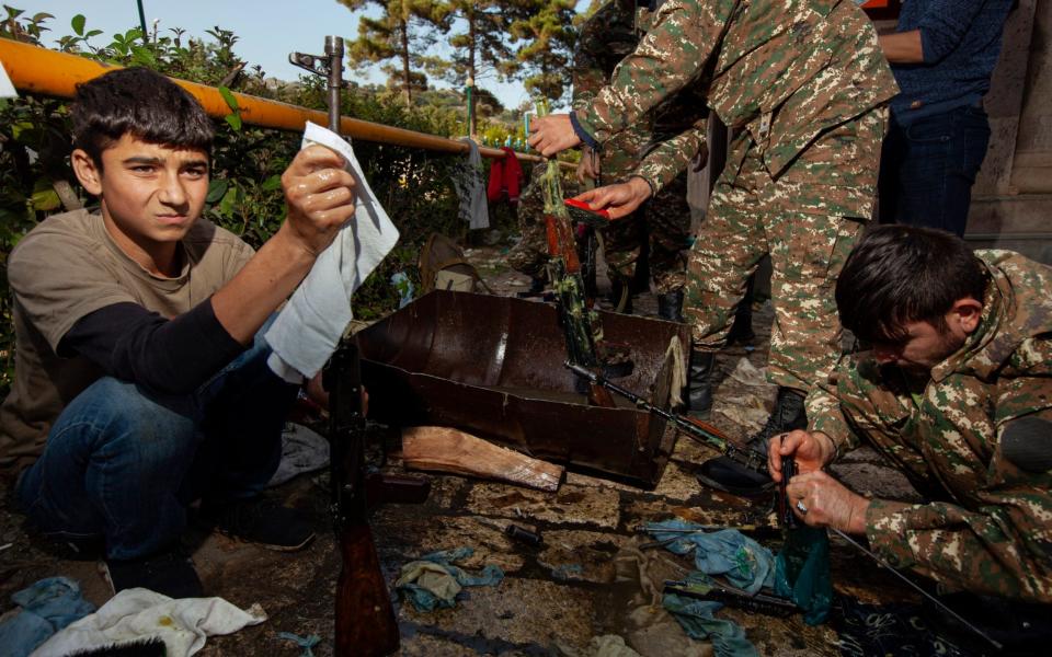 Young volunteers help soldiers to clean Kalashnikovs in Nagorno-Karabakh - AP Photo/Karen Mirzoyan