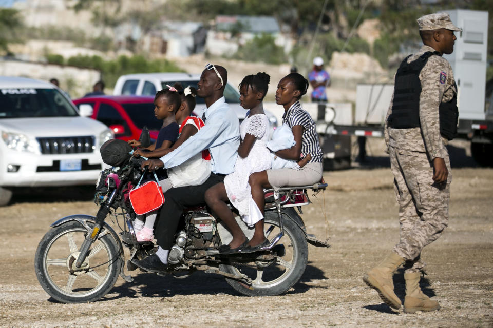 Residents ride on a motorcycle through Titanyen, a mass burial site, prior to a memorial service honoring the victims of the 2010 earthquake, in Port-au-Prince, Haiti, Sunday, Jan. 12, 2020. Sunday marks the 10th anniversary of the devastating 7.0 magnitude earthquake that destroyed an estimated 100,000 homes across the capital and southern Haiti, including some of the country's most iconic structures. (AP Photo/Dieu Nalio Chery)