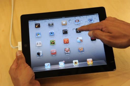 A staff member poses with the new iPad 2 at the Apple store in central London. The Washington Post, Dow Jones, Time Inc. and other news organizations have accused iPad news reader Zite of copyright infringement and told the Canadian startup to stop displaying their articles