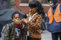 FILE - In this Monday, March 29, 2021, file photo, Jenea Edwards, of the North Side, helps her son Elijah, 9, in the third grade, with his mask before heading into Manchester Academic Charter School on the first day of in-person learning via a hybrid schedule, in Pittsburgh. Dozens of school districts around the country have eliminated requirements for students to wear masks, and many more are likely to ditch mask requirements before the next academic year. (Andrew Rush/Pittsburgh Post-Gazette via AP, File)