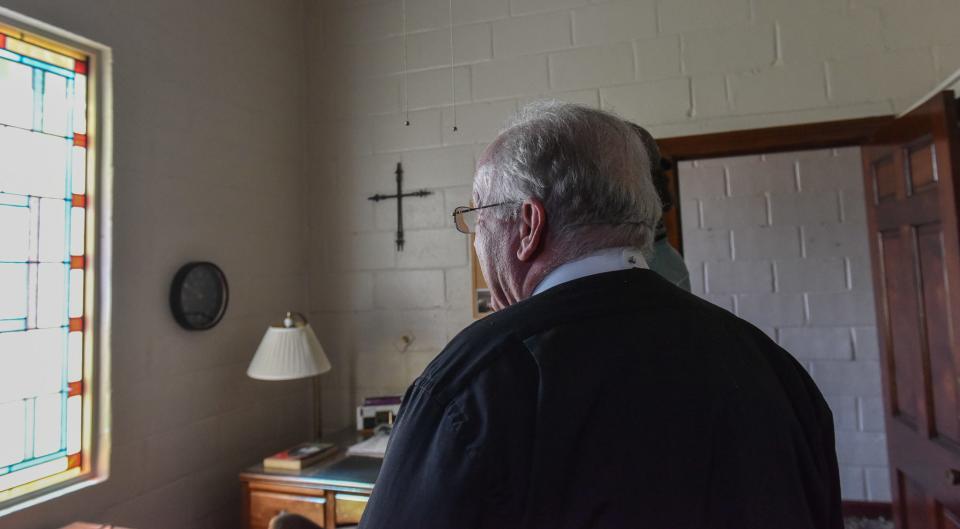 Greg Proctor, the rector of the Chapel of the Cross Episcopal Church, pauses in front of the lone remaining stained-glass window in the church in Rolling Fork, Miss., Sunday, March 26, 2023.