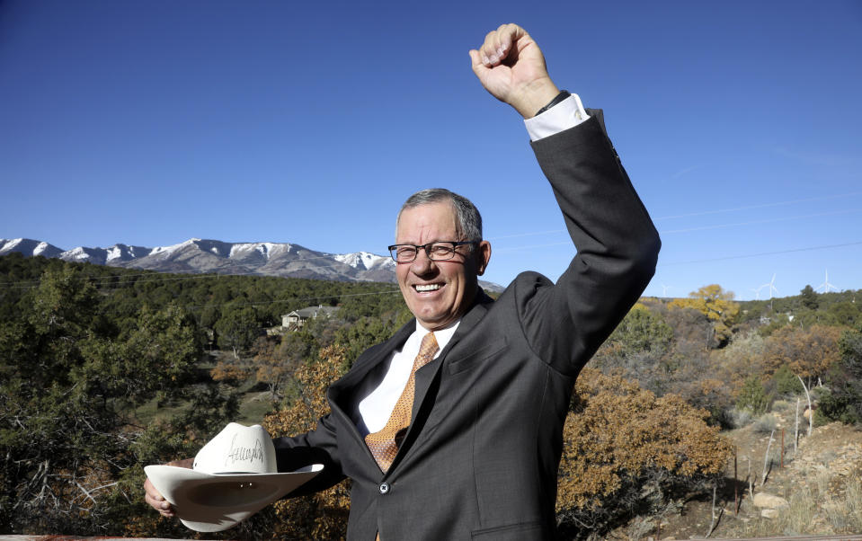 FILE - In this Oct. 26, 2018 file photo, Bruce Adams, Republican chair of the San Juan County commission, poses with the hat signed by President Donald Trump after signing a proclamation to shrink the size of Bears Ears and Grand Staircase Escalante national monuments at his home in Monticello, Utah. A newly unveiled advisory committee that will help make management decisions for the downsized Bears Ears National Monument in southern Utah has become the latest flashpoint in a long-running debate over lands considered sacred to Native Americans as monument supporters cry foul about being left off the panel. (AP Photo/Rick Bowmer, File)