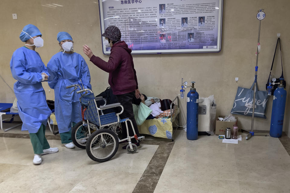 Medical workers talk to a woman as an elderly woman receives medical treatment in the hallway of the emergency ward in Beijing, Thursday, Jan. 19, 2023. China on Thursday accused "some Western media" of bias, smears and political manipulation in their coverage of China's abrupt ending of its strict "zero-COVID" policy, as it issued a vigorous defense of actions taken to prepare for the change of strategy. (AP Photo/Andy Wong)