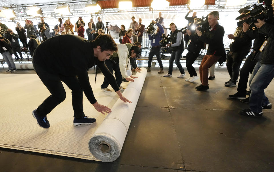 Trabajadores desenrollan la alfombra durante los preparativos para la 95a edición de los Premios de la Academia, el 8 de marzo de 2023, fuera del Teatro Dolby en Los Angeles. (Foto AP/Chris Pizzello)