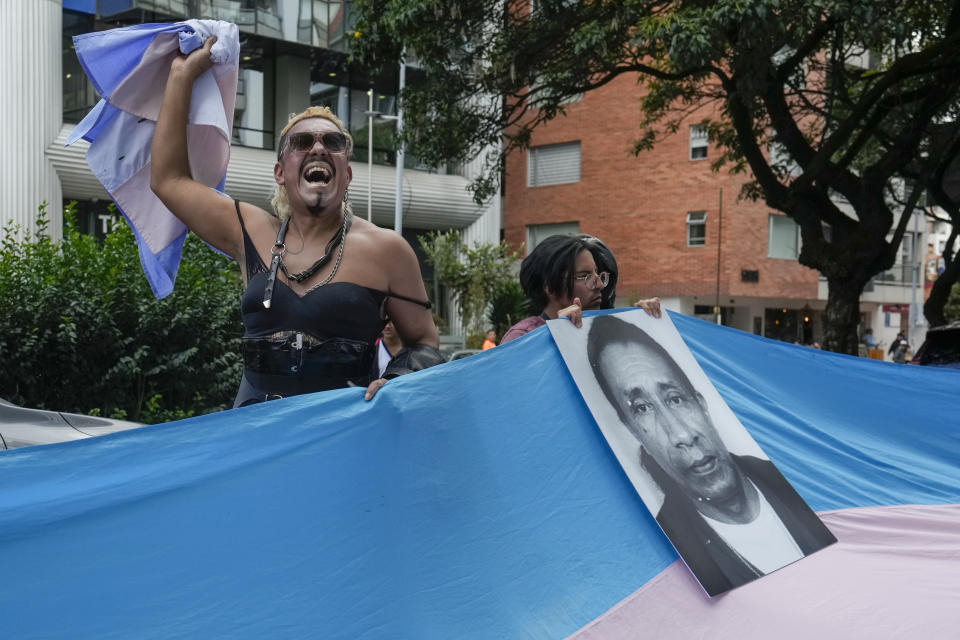 Con una foto de una persona trans que murió en circunstancias sospechosas, integrantes de la comunidad LGBTI+ de Ecuador protestan contra un decreto del gobierno de Perú que clasifica siente identidades de género como enfermedades mentales, en las afueras de la embajada peruana en Quito, Ecuador, el viernes 17 de mayo de 2024. (AP Foto/Dolores Ochoa)