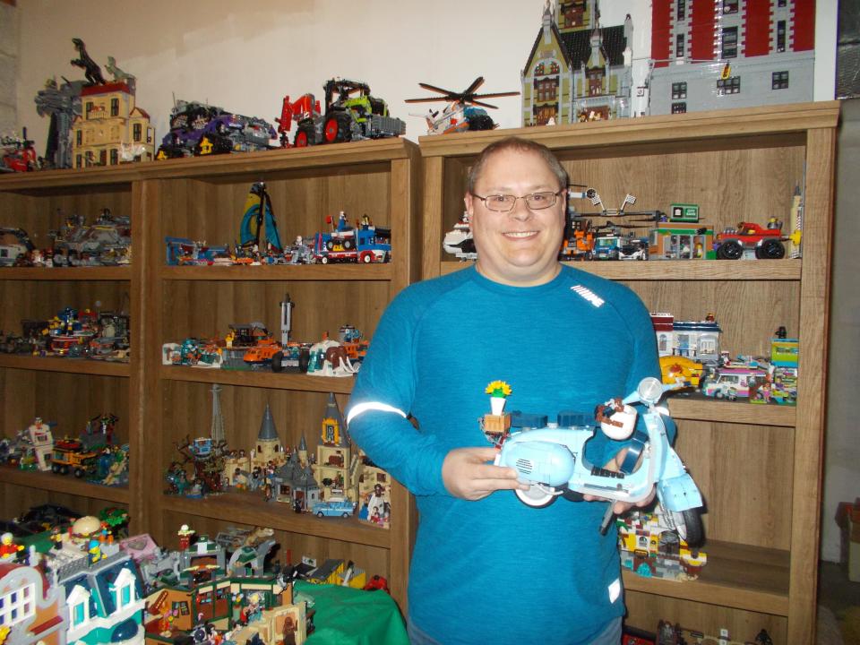 Doug Meyer holds a Vespa blue scooter, which is part of his Lego collection at home.