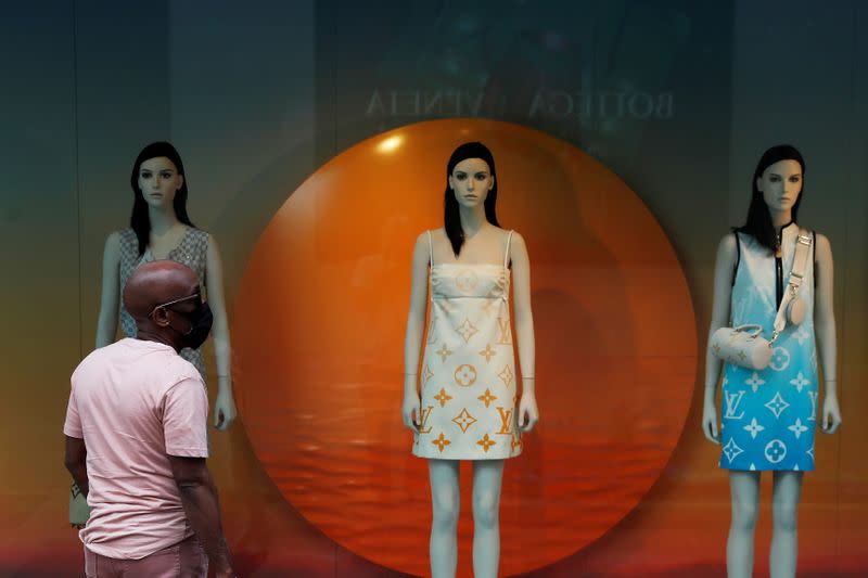 FILE PHOTO: A man wearing a protective mask stands outside Louis Vuitton luxury store at the Americana Manhasset open-air shopping complex in Manhasset, New York