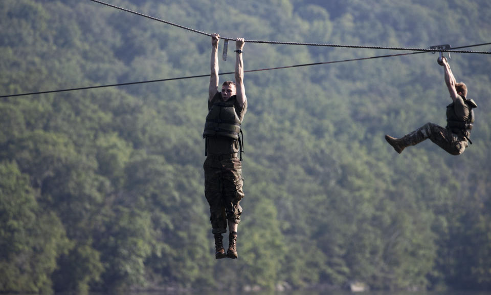 Cadets hang above a lake as they navigate a water obstacle course, Friday, Aug. 7, 2020, in West Point, N.Y. The pandemic is not stopping summer training at West Point. Cadets had to wear masks this year for much of the training in a wooded area just beyond the main gates of the U.S. Military Academy. (AP Photo/Mark Lennihan)