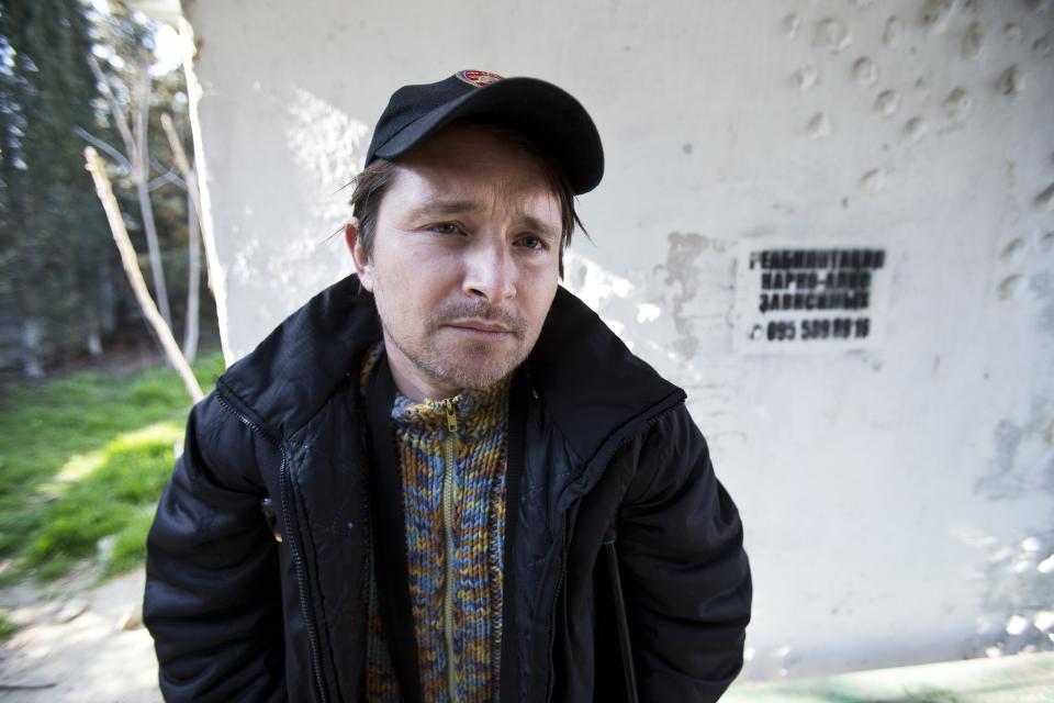 In this photo taken Tuesday, April 1, 2014, Anton, a patient of treatment for drug addiction, poses at a bus stop with an advert reading "Rehabilitation of drug and alcohol addicts" in Sevastopol, Crimea. Across the Black Sea peninsula, some 800 heroin addicts and other needle-drug users take part in methadone programs, seen as an important part of efforts to curb HIV infections by taking the patients away from hypodermic needles that can spread the AIDS-causing virus. After Russia's annexation of Crimea methadone was banned. The ban could undermine years of efforts to reduce the spread of AIDS in Crimea. (AP Photo/Pavel Golovkin)