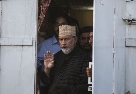 Tahir ul-Qadri, Sufi cleric and leader of political party Pakistan Awami Tehreek (PAT),waves to supporters as he walks out his container to address supporters in front of the Parliament house building during the Revolution March in Islamabad August 28, 2014. REUTERS/Faisal Mahmood