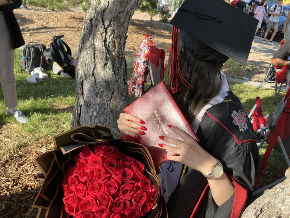 A 17-year-old graduate from West High School poses for a picture after a ceremony at the University of Utah in Salt Lake City on June 9, the day after President Joe Biden announced humanitarian parole would be extended for Afghan arrivals like her. Her face is not shown to protect her family in Afghanistan. | Andrea Smardon, KSL Podcasts