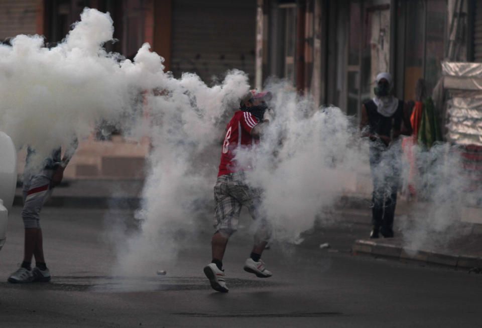 A Bahraini anti-government protester runs through tear gas fired by riot police during clashes after a march to recognize protesters who have lost their vision after being shot in the eye with bird shot, rubber bullets or tear gas canisters during past clashes Thursday, June 7, 2012, in Sitra, Bahrain. (AP Photo/Hasan Jamali)