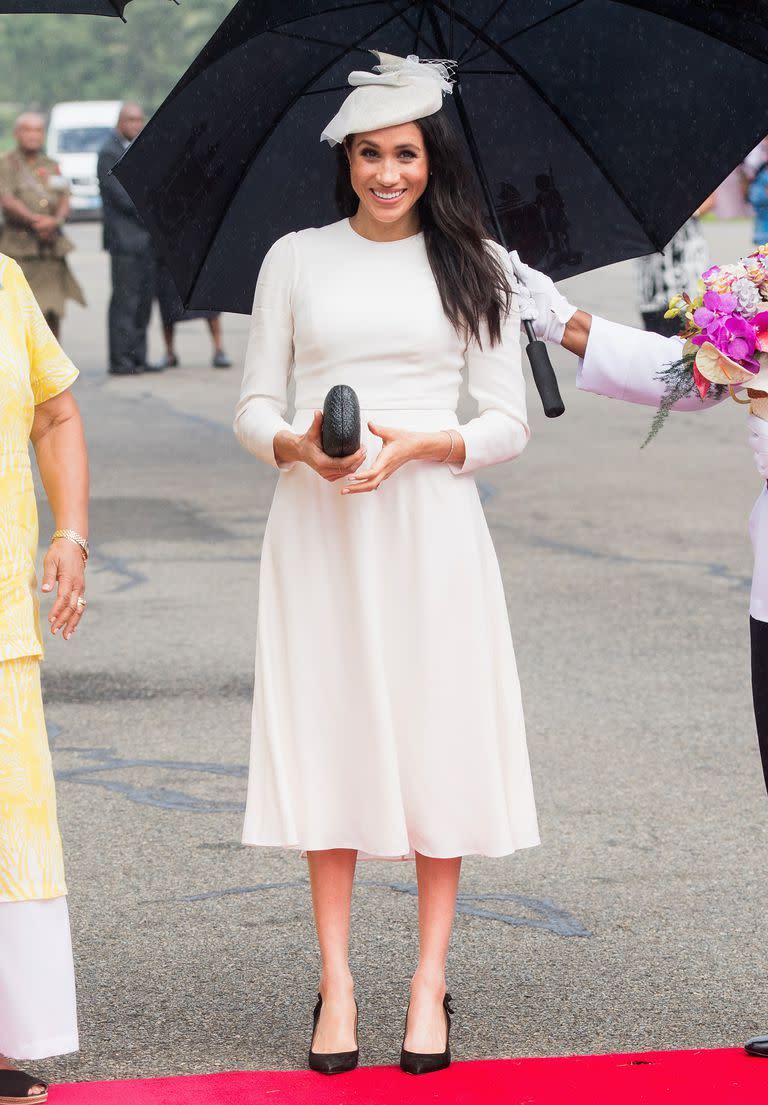 <p>Arriving in Fiji, Meghan Markle recreated her wedding day look, opting for a formal <a href="https://www.net-a-porter.com/gb/en/Shop/Designers/Zimmermann/Clothing?pn=1&npp=60&image_view=product&dScroll=NaN&colourFilter=White&excludeFilters=false" rel="nofollow noopener" target="_blank" data-ylk="slk:Zimmermann ivory dress;elm:context_link;itc:0;sec:content-canvas" class="link ">Zimmermann ivory dress</a> with a Stephen Jones matching-coloured hat. Stepping off the plane with her husband, Prince Harry, the Duchess of Sussex looked effortlessly chic as she met with well-wishers, showing off her favourite <a href="https://www.net-a-porter.com/gb/en/Shop/Designers/Kayu?cm_mmc=GoogleUK--c-_-NAP_EN_UK_London-_-NAP+-+INTL+-+London+-+Designer_Kayu+-+BT--Kayu+-+Bags+-+Clutches-_-%2Bkayu+%2Bclutches_b_aud-314946096719%3Akwd-321161427809_INTL&gclid=Cj0KCQjwjbveBRDVARIsAKxH7vnRNu6gQL1Y6n9L7vmJz6nseiM8RHU_EXza9Ldrg8mIBPzxya56AoAaAn7bEALw_wcB&gclsrc=aw.ds&pn=1&npp=60&image_view=product&dScroll=0" rel="nofollow noopener" target="_blank" data-ylk="slk:Kayu box clutch;elm:context_link;itc:0;sec:content-canvas" class="link ">Kayu box clutch</a> and <a href="https://www.net-a-porter.com/Shop/Search?designerFilter=566&keywords=Tabitha+Simmons&termUsed=Tabitha+Simmons" rel="nofollow noopener" target="_blank" data-ylk="slk:Tabitha Simmons;elm:context_link;itc:0;sec:content-canvas" class="link ">Tabitha Simmons</a> heels for the occasion.</p>