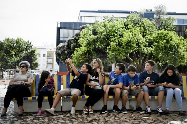 Participants in the "Blue Summer" project take selfies as they wait to visit Lisbon's Oceanarium on their last day of holiday in Portugal