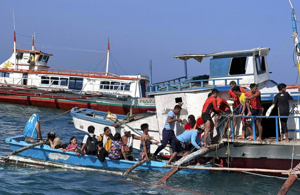 In this handout photo provided by the Philippine Coast Guard, rescuers assist passengers board a boat after a passenger ferry began to take on water in the vicinity waters off Corcuera, Romblon province, central Philippines on Saturday Aug. 5, 2023. One person died and more than 100 had to be rescued after a ferry King Sto. Nino 7 in the central Philippines struck floating debris at sea and took on water Saturday, police said. (Philippine Coast Guard via AP)