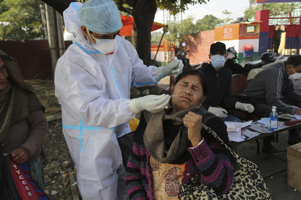 A health worker collects a swab sample from a woman to test for COVID-19 by a road side in Jammu, India, Monday, Nov.30, 2020. India is second behind the U.S. in total coronavirus cases. Its recovery rate is nearing 94%. (AP Photo/Channi Anand)