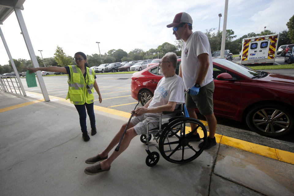 Alex Filipovski of Martin County Fire and Rescue helps evacuee Don Penlonas wheel into an evacuation shelter for people with special needs, in preparation for Hurricane Dorian, at Dr. David L. Anderson middle School in Stuart, Fla., Sunday, Sept. 1, 2019. Some coastal areas are under a mandatory evacuation since the path of the storm is still uncertain. (AP Photo/Gerald Herbert)