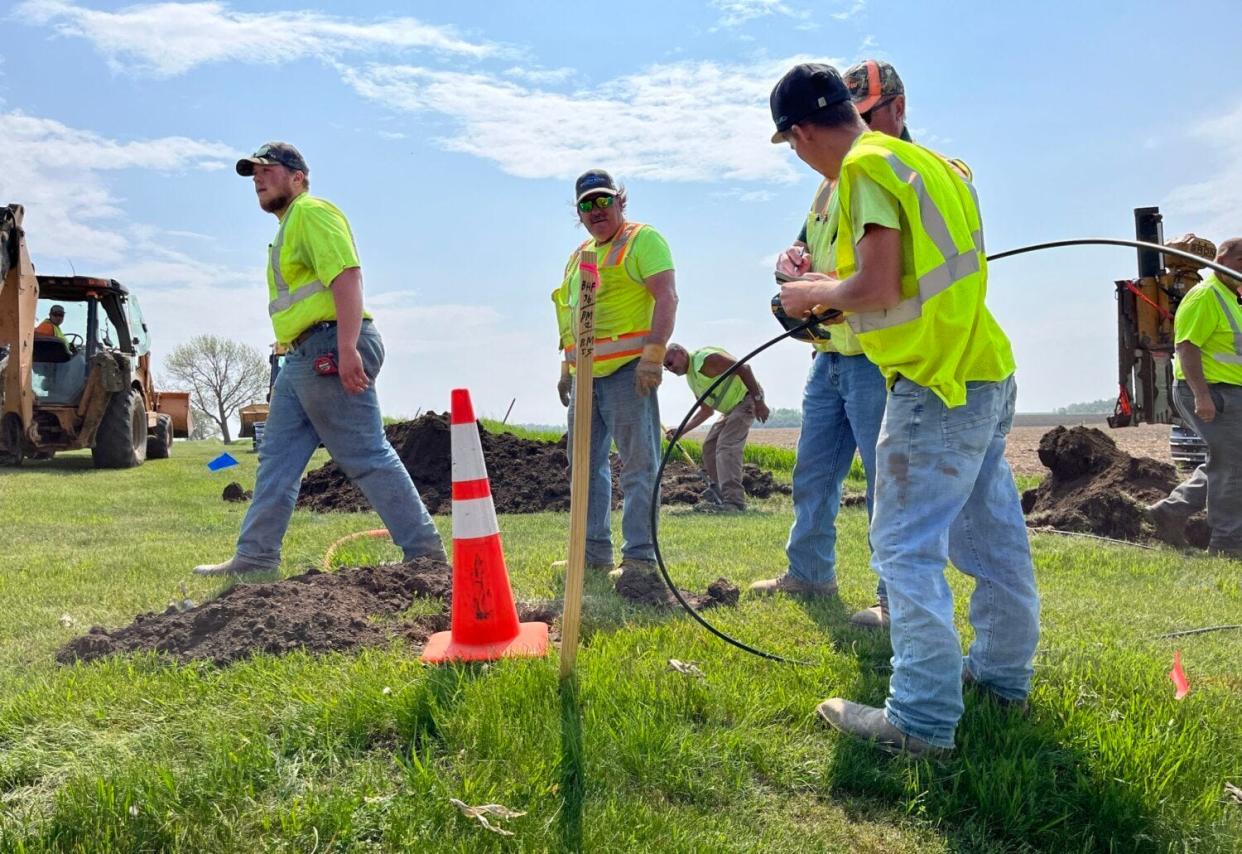 Workers lay fiber-optic cable at a broadband expansion site near Colton