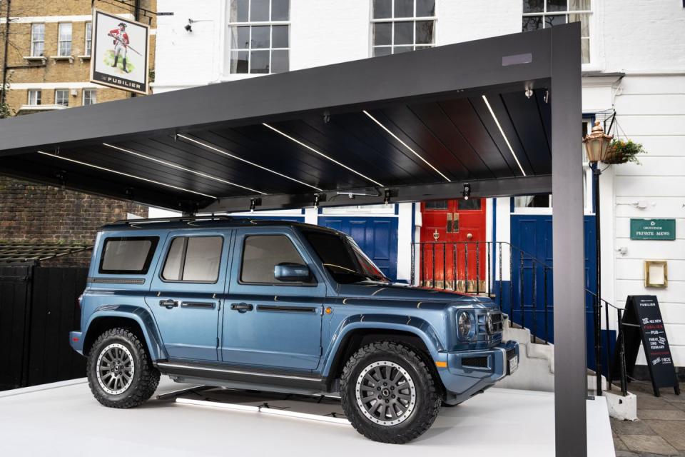 a blue ineos fusilier parked under a covered awning