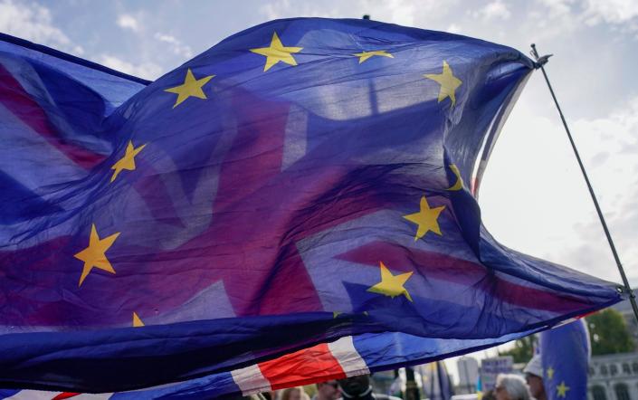 A Union flag flies behind a European Union flag, outside the Houses of Parliament