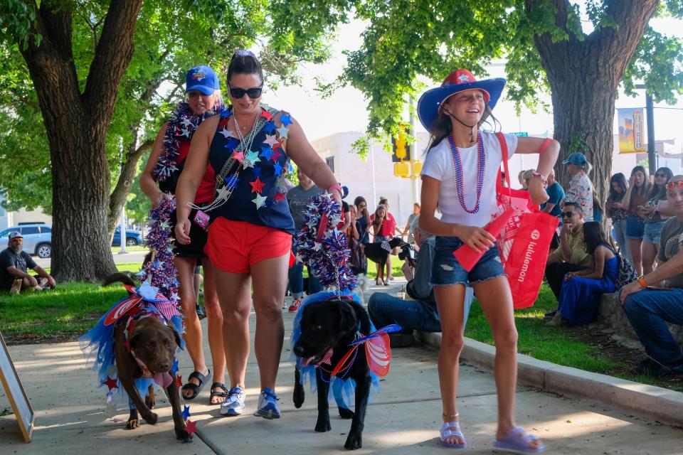 Evie Granado leads the dynamic duo of Momo (brown Labrador) escorted by Stephanie Granado  and Duke (black Labrador) escorted by Kara Kennedy during the patriotic pet parade Saturday morning at the Amarillo Community Market in downtown Amarillo.