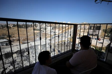 Palestinians watch as an Israeli military bulldozer demolishes a building near a military barrier in Sur Baher, a Palestinian village on the edge of East Jerusalem in an area that Israel captured and occupied in the 1967 Middle East War