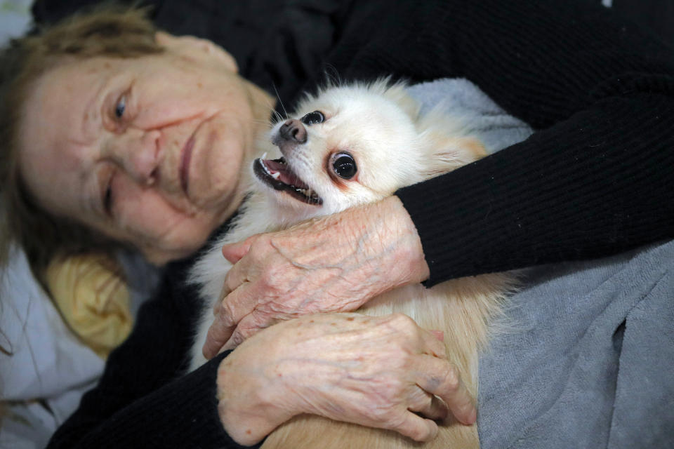 A refugee who fled the Russian invasion from neighboring Ukraine comforts her dog as they sit in a ballroom converted into a makeshift refugee shelter at a 4-star hotel & spa, in Suceava, Romania, Friday, March 4, 2022.(AP Photo/Andreea Alexandru)