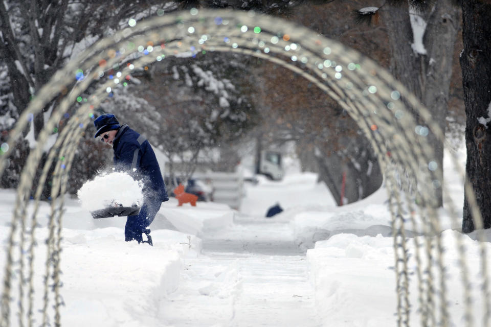 A Christmas outdoor decoration placed over a sidewalk frames Bjorn Gronbeck as he removes snow from a driveway on 17th Street Thursday, Dec. 27, 2018, in Bismarck, N.D. Forecasters posted a blizzard warning for parts of the Dakotas and Minnesota as a major winter storm delivered heavy snow and gusty winds to the region. (Mike McCleary/The Bismarck Tribune via AP)