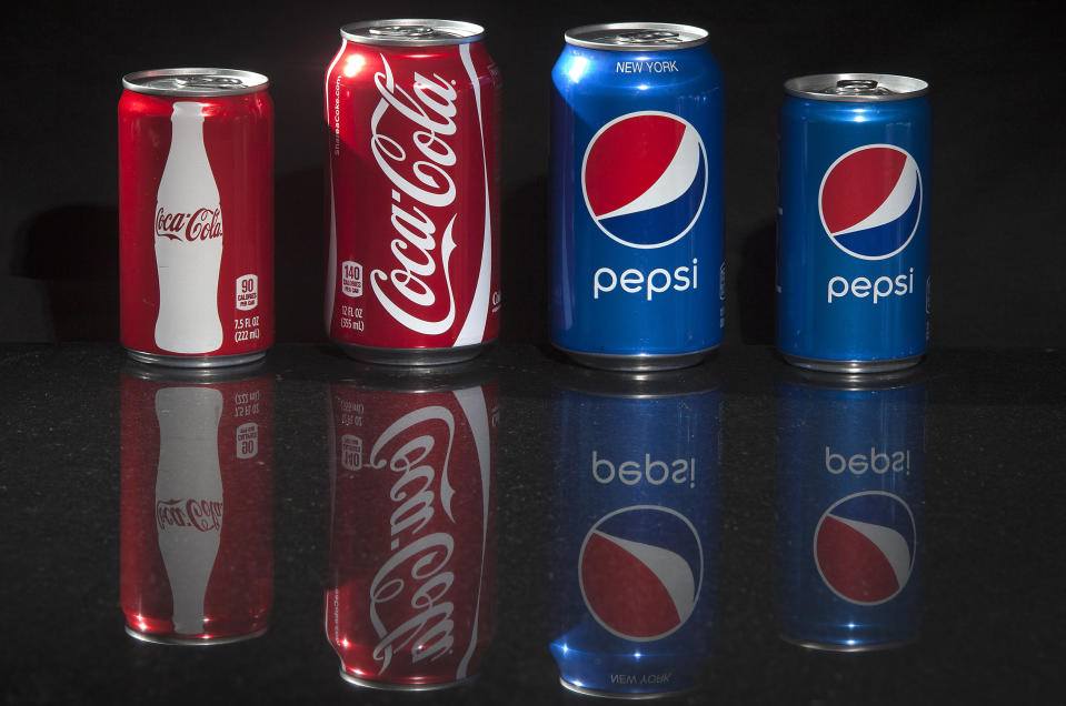 Regular and mini cans of Coke and Pepsi are pictured in this photo illustration in New York August 5, 2014. U.S. soft drink companies are betting that soda drinkers like Krueger and their willingness to buy smaller cans, even for a higher unit price, will be a potential antidote to weak sales as consumers shift away from sugary soft drinks. The mini-can is the latest move by food and beverage companies to boost their product offerings of smaller portion sizes that supposedly help consumers limit their caloric intake - even if there are signs that some end up reaching for another package or can. REUTERS/Carlo Allegri (UNITED STATES - Tags: SOCIETY BUSINESS)