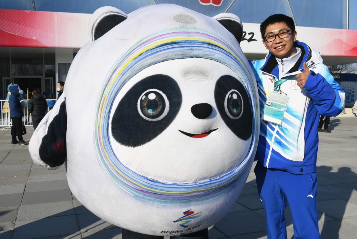 Bi Tingzhu, venue operation team member of Beijing 2022 Winter Olympics, takes a photo with Bing Dwen Dwen outside the National Aquatics Centre the 