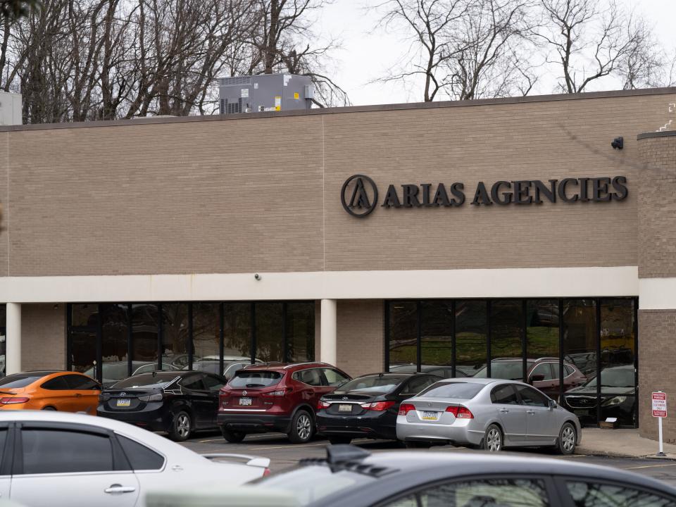 One story building labeled Arias Agencies with a parking lot in front.