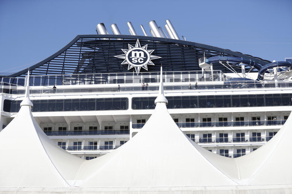 Cruise ship passengers aboard the MSC Divina look off the balconies as they wait to shove off at PortMiami, Friday, Feb. 28, 2020, in Miami. The spread of a new coronavirus from China is disrupting the cruise industry in the midst of its busiest season for bookings. (AP Photo/Wilfredo Lee)