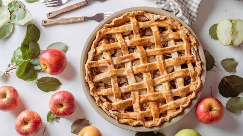 Apple pie surrounded by apples and leaves