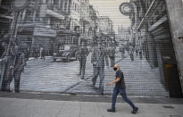 A man walks in front of a shuttered outfit store during a quarantine imposed by the state government to help contain the spread of the new coronavirus in Sao Paulo, Brazil, Monday, June 1, 2020. (AP Photo/Andre Penner)