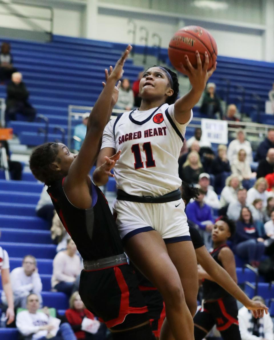 Sacred Heart’s ZaKiyah Johnson (11) shoots under the basket against Manual’s Lexi Weaver (1) during the Girls LIT Championship at the Valley High School gym in Louisville, Ky. on Jan. 28, 2023.  