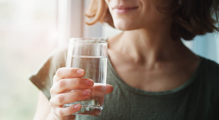 A photo of a woman holding a glass of water.