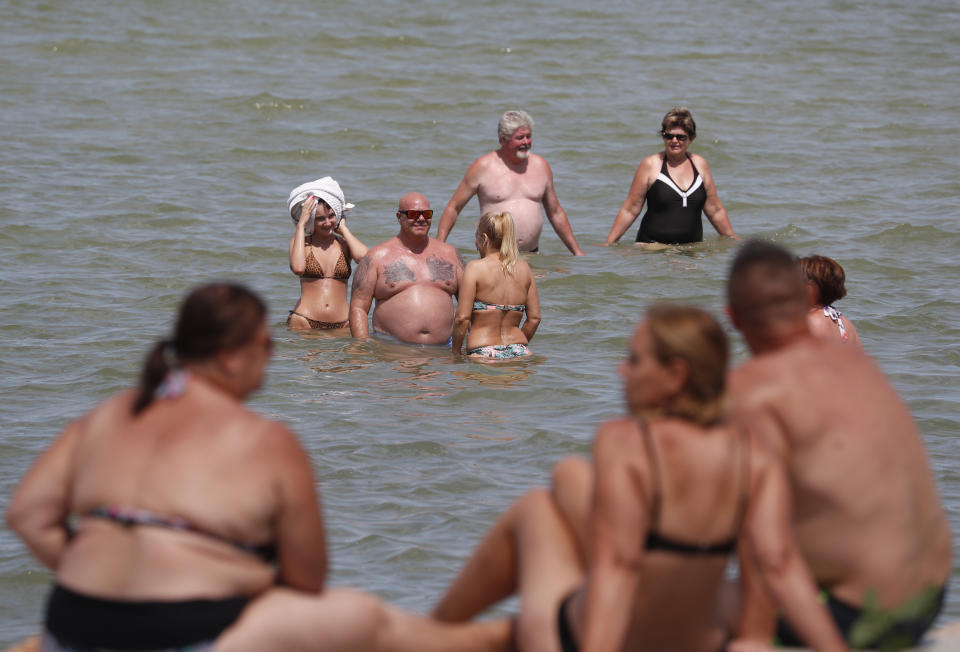 People enjoy the sunny day in the Lake Velence in Agard, Hungary, Sunday, Aug. 8, 2021. Activists and environmental experts in Hungary say the effects of climate change and insufficient infrastructure are colliding to threaten the country’s third largest natural lake with an economic and ecological crisis. Lake Velence has lost nearly half of its water in the last two years as hot, dry summers have led to increased evaporation and deteriorating water quality. (AP Photo/Laszlo Balogh)