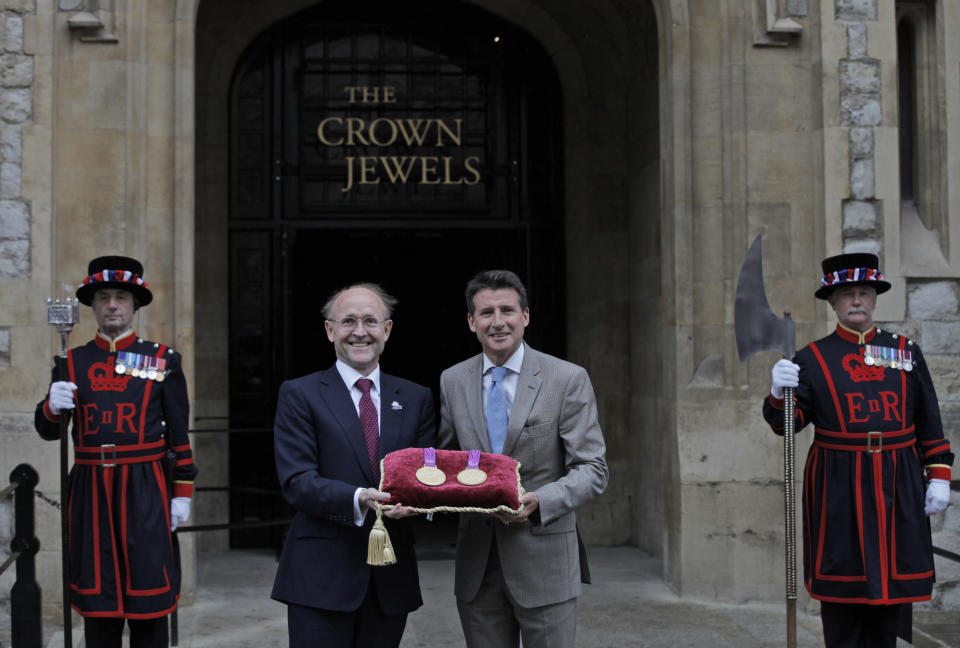 Sebastian Coe, centre right, chairman of the London 2012 Organizing Committee, and Jan du Plessis, left, Rio Tinto mining company chairman, pose for the photographers holding a gold medal of the Games, during a photo op at the Tower of London, in London, Monday, July 2, 2012 The company is responsible for the production of the precious metals for the London 2012 Games, and has handed over the final Olympic and Paralympic medals to LOCOG for secure storage in the vaults at the Tower of London during the Games. The gold, silver and bronze medals which will be awarded to the athletes at Games-times, will remain there until they are needed for the Victory Ceremonies. In total, 4,700 medals have been produced and will be awarded in 805 Victory Ceremonies that will take place in over 30 London 2012 venues across the UK. (AP Photo/Lefteris Pitarakis)