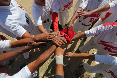 Members of Family Rose softball team put their hands together before a match at Lecuna Avenue softball pitch in Caracas, Venezuela, March 24, 2019. "After the game we always had a few beers. But now they are too expensive," said Felix Babaza. REUTERS/Ivan Alvarado