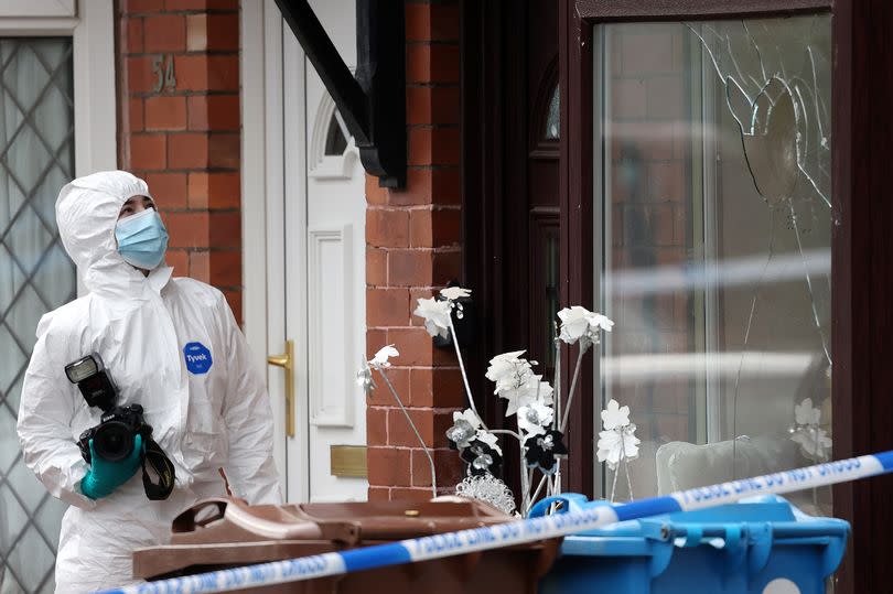 Forensic officers examine a smashed window at a home on Prince Edward Avenue