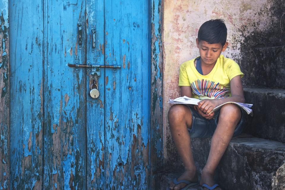 A boy reads a book on a set of steps.