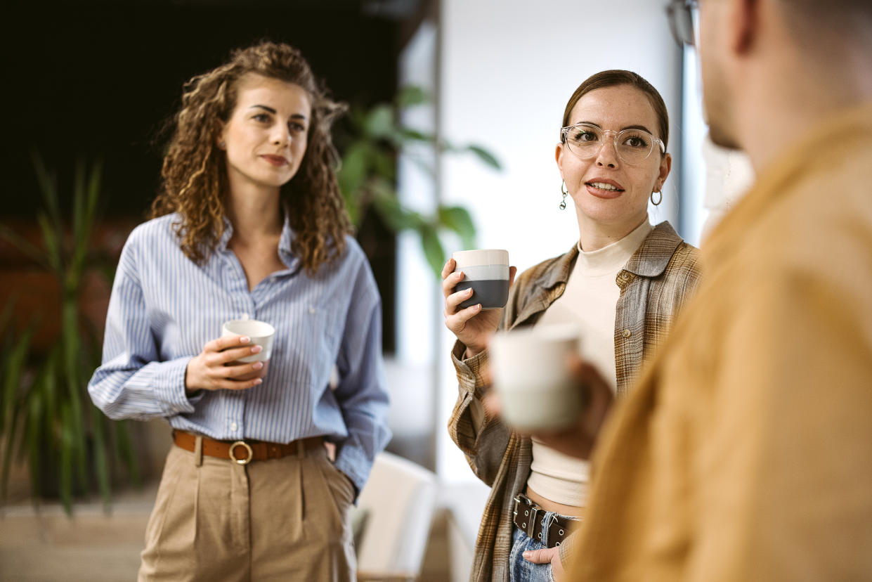 A group of colleagues is taking a break at work, drinking coffee, talking.