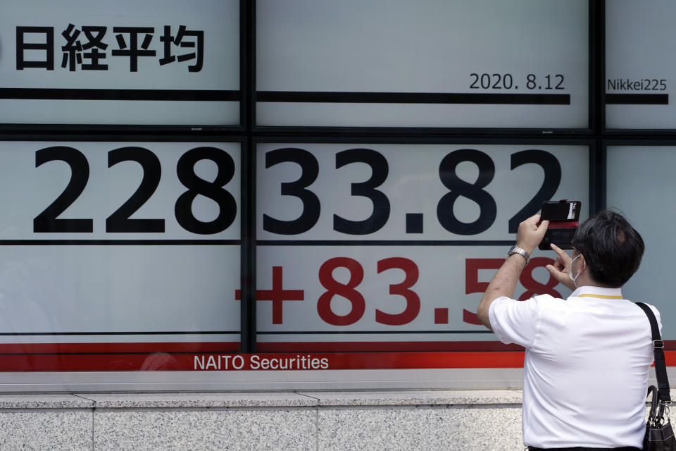 A man photographs an electronic stock board showing Japan's Nikkei 225 index at a securities firm in Tokyo Wednesday, Aug. 12, 2020. Shares were mostly lower in Asia on Wednesday after Wall Street pumped the brakes on its recent rally. (AP Photo/Eugene Hoshiko)