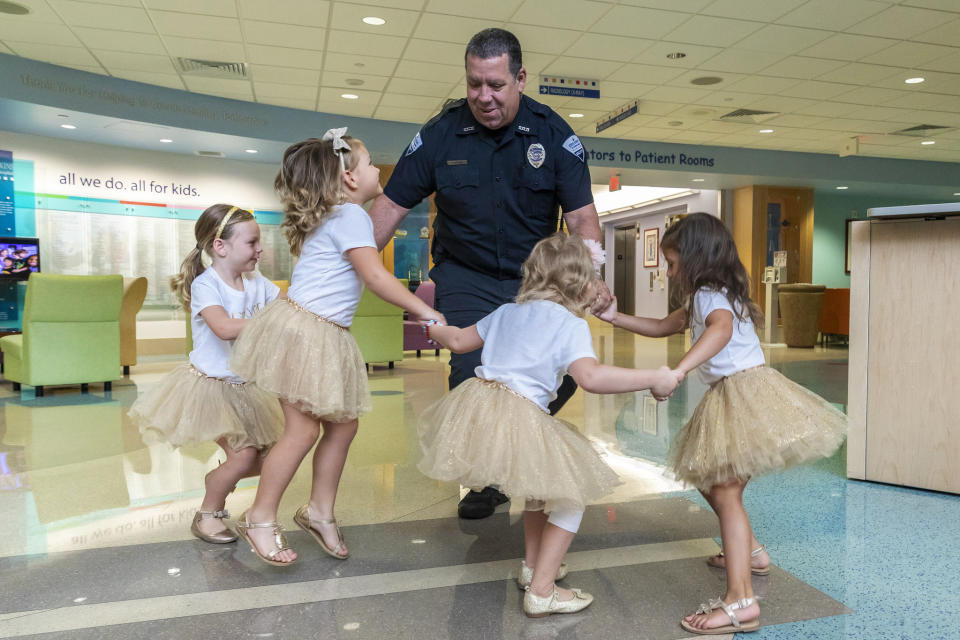 In this photo provided by Johns Hopkins All Children’s Hospital, security guard David Dean dances with McKinley Moore, Avalynn Luciano, Lauren Glynn and Chloe Grimes at the hospital in St. Petersburg, Fla., Aug. 9, 2018. The girls, who were diagnosed with cancer in 2016 and became fast friends while undergoing treatment, reunite every year. (Allyn DiVito/John Hopkins All Children's Hospital via AP)