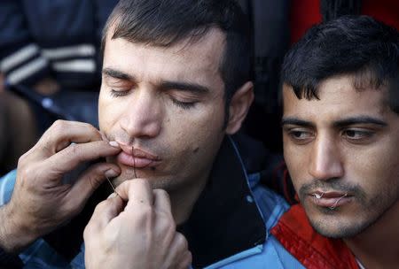 Stranded Iranian migrant has his mouth sewed shut by a colleague during a protest at the Greek-Macedonian border near the Greek village of Idomeni November 26, 2015. REUTERS/Yannis Behrakis