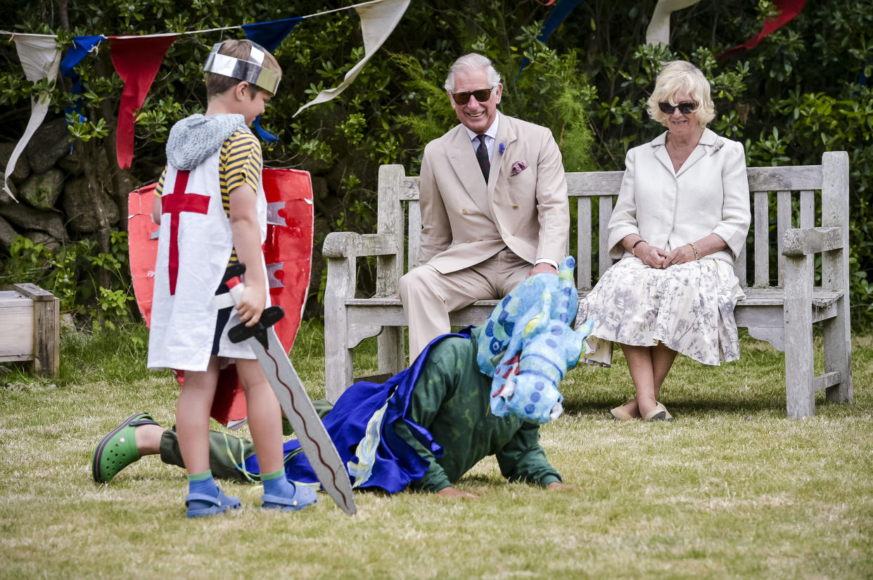 Charles and Camilla watch a performance of St George and the Dragon by school pupils