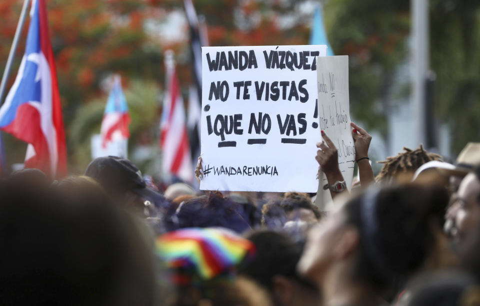 A protester holds a sign that reads in Spanish "Wanda Vazquez. Don't get dressed up. You're not going!," referring to who will be the next governor, as people demand the resignation of Justice Secretary Wanda Vazquez outside the Department of Justice in San Juan, Puerto Rico, Monday, July 29, 2019. Less than four days before Gov. Ricardo Rosselló steps down, no one knows who will take his place and his constitutional successor Wanda Vázquez said Sunday that she didn't want the job. (AP Photo/Brandon Cruz González)